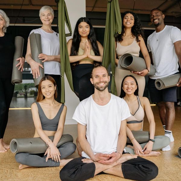 Group of people smiling during a light and joyful yoga class.